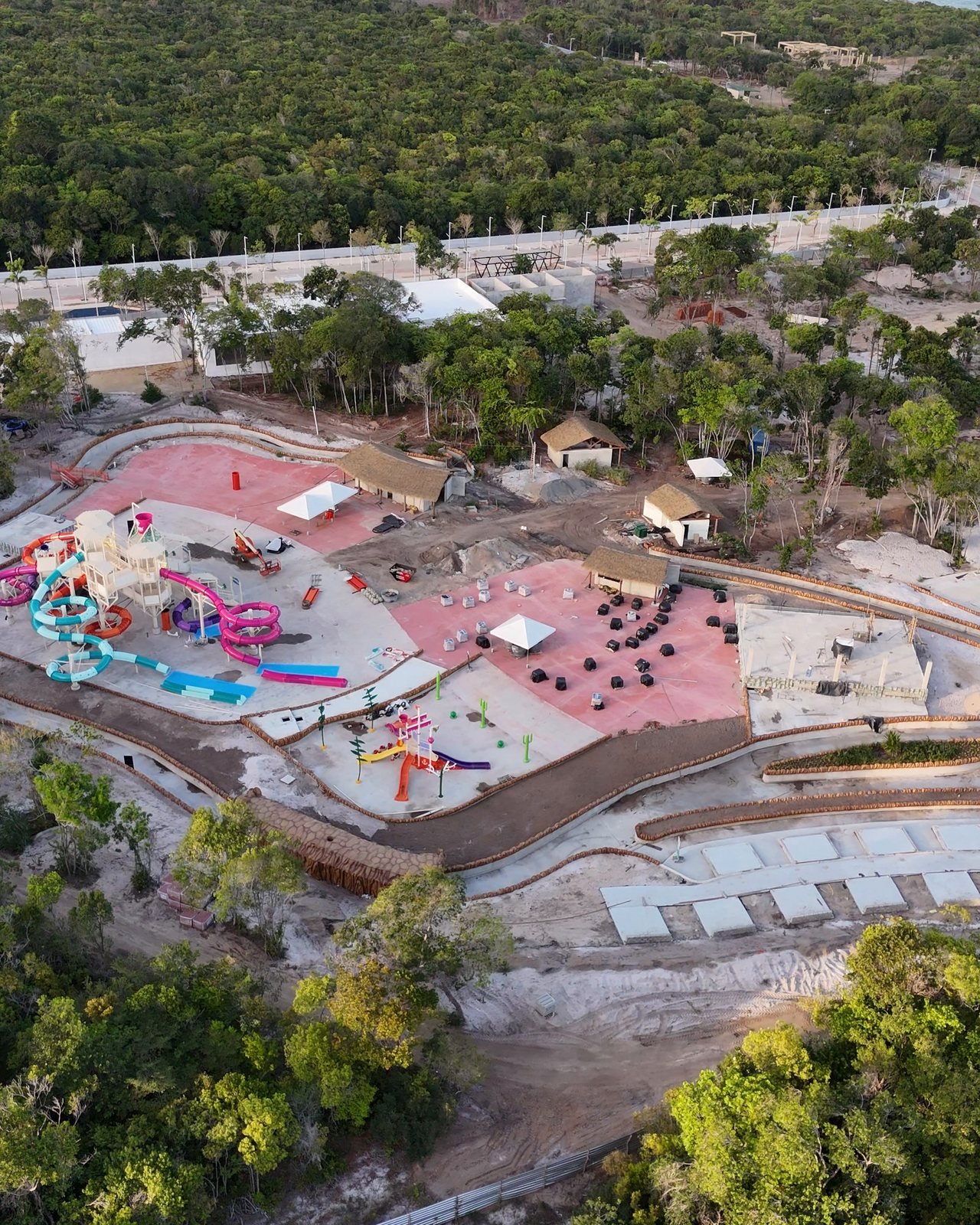 Imagem aérea do parque aquático Acquai em construção, com as piscinas e os brinquedos no meio da mata