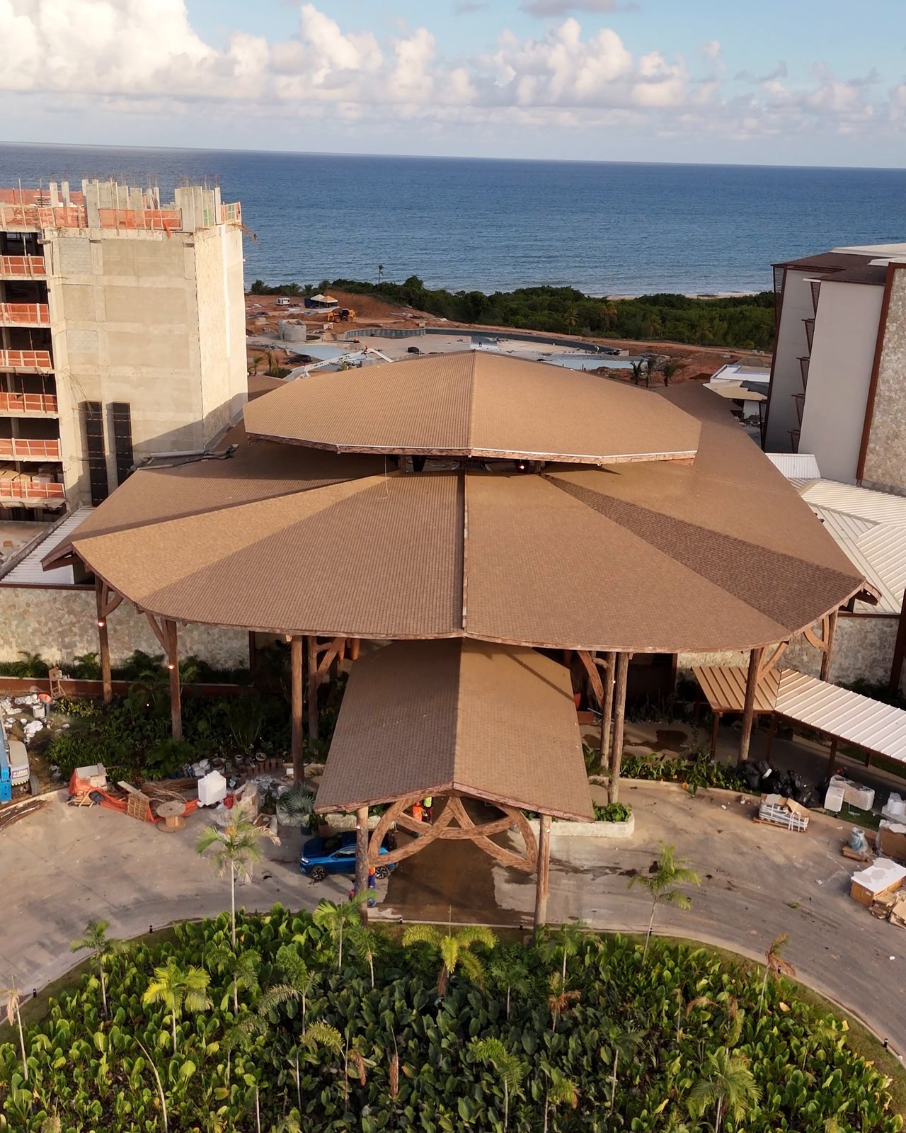 Cobertura de palha do Tauá Resort João Pessoa vista de cima, com o mar do Cabo Branco ao fundo e um bloco em obra ao lado