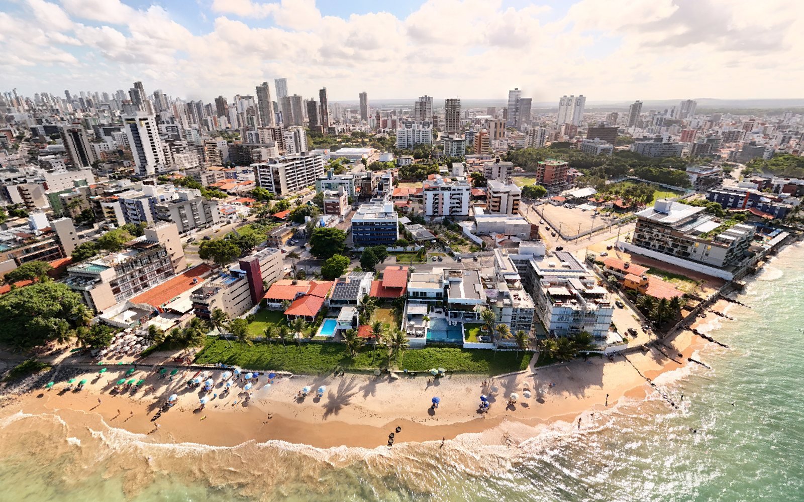 Vista aérea da praia do Bessa, em João Pessoa, com casas de frente para o mar e a água verde