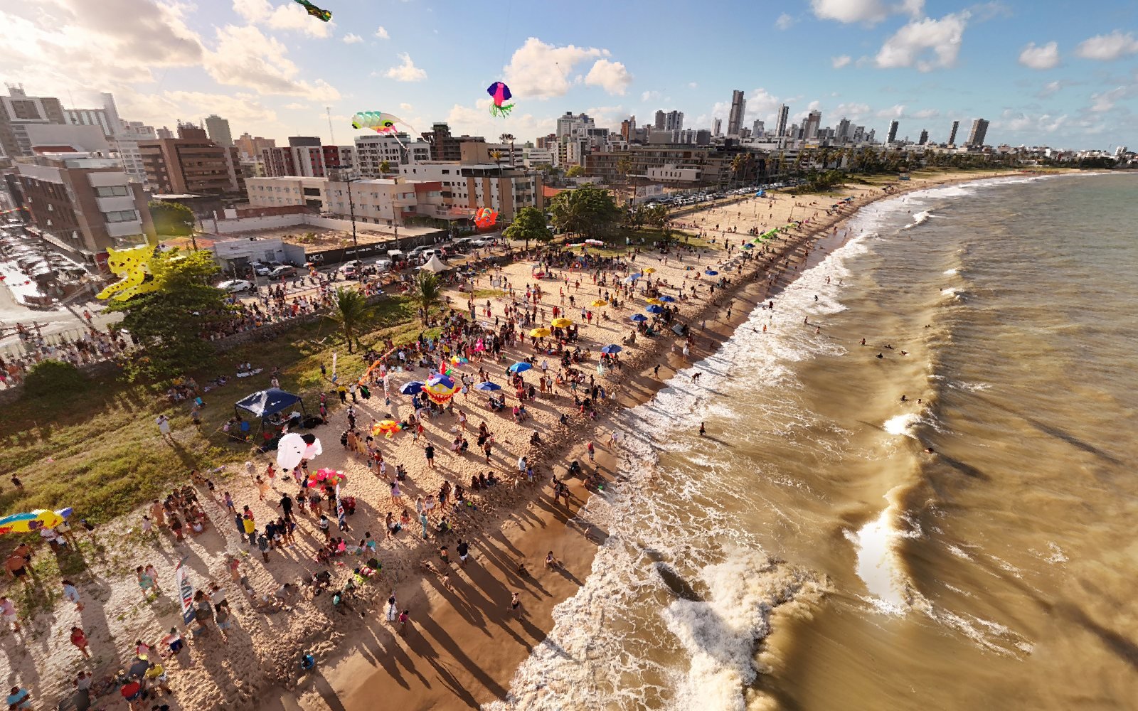 Vista aérea com pipas coloridas no céu de Manaíra, em João Pessoa, sobre a praia cheia e o mar