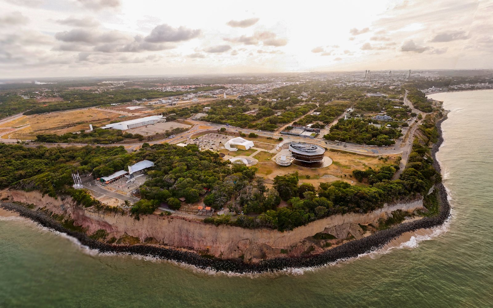 Vista aérea da Ponta do Seixas, com a falésia contornando o continente, a Estação Cabo Branco e a orla de João Pessoa ao fundo